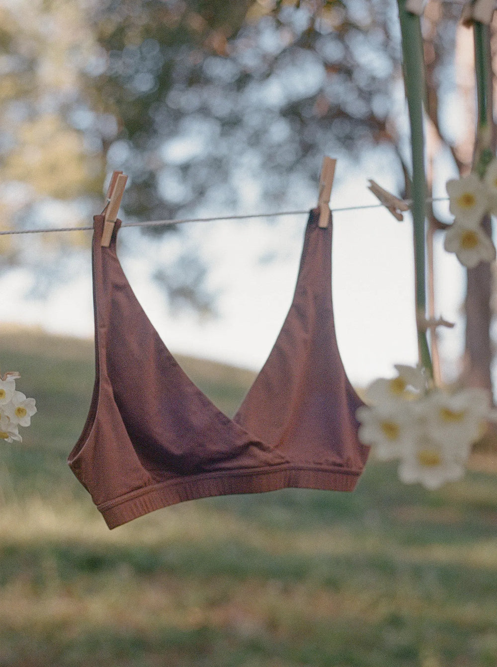 Cleo Crossover Bra in Earth hanging outdoors among flowers